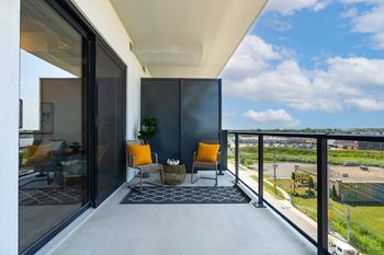 A balcony with a chair and a table with a plant on it.